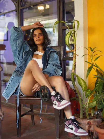 A relaxed moment on set. Srishti Shrivastava takes a break during a shoot, showcasing her cool street style look in a casual, candid setting.