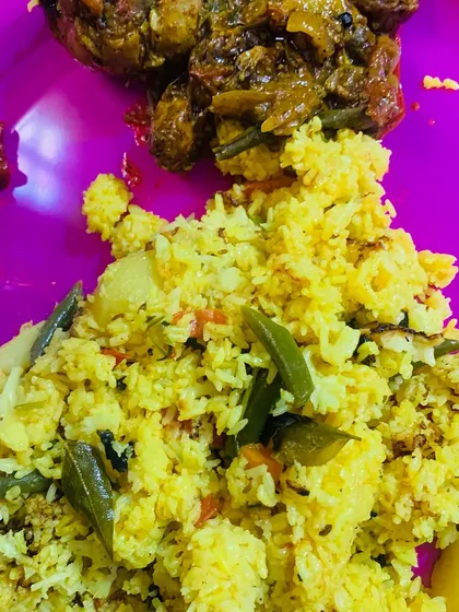 A plate of vegetable pulao served with a spicy chicken curry and a dollop of red chilli chutney.