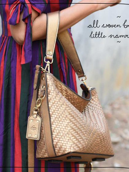 A close-up of the All Woven Bronze Little Namrata. You can see the beautiful texture of the hand-woven metallic leather and the custom monogrammed tag, a small detail that makes the bag uniquely yours.