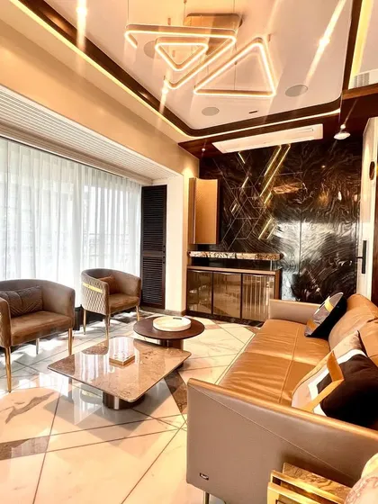 A view of a cozy yet luxurious bedroom sitting area. The design features a mix of textures, from the patterned wood wall to the dark marble feature wall and the geometric inlay in the flooring.