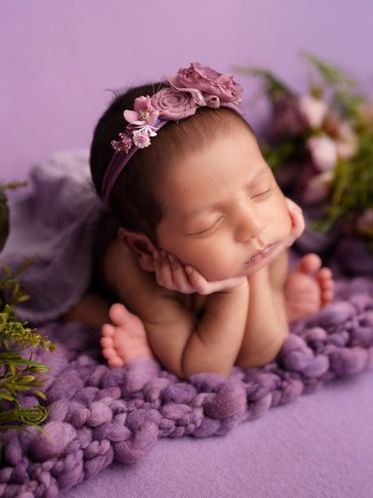 Another variation of the 'chin on hands' pose, surrounded by soft purple flowers, creating a dreamy and peaceful atmosphere.