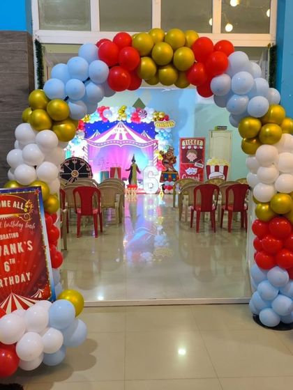 A grand entrance to a carnival-themed party, with a multi-colored balloon arch and themed signage.