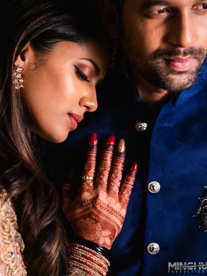 An intimate couple portrait where the bride's henna-adorned hand is a focal point. The dark stain adds a layer of tradition and beauty to this modern, romantic shot.