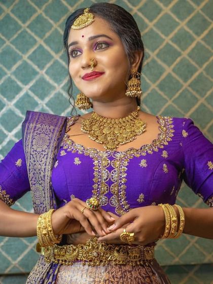 An elegant pose showcasing the intricate embroidery of the blouse and the matching gold jewellery.