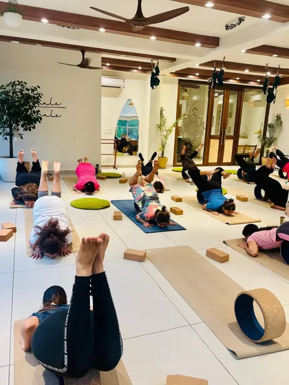 A class practices a supported headstand variation, building strength and confidence for inversions.