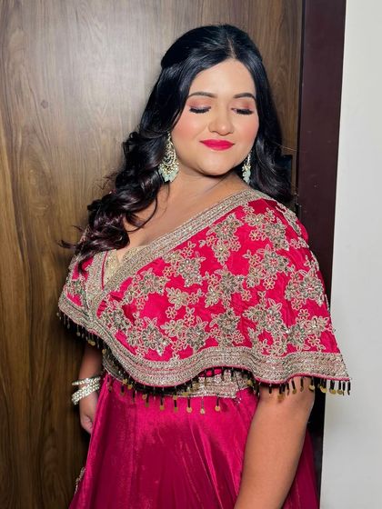 A glamorous party look with a bold red lip and soft curls, perfect for a reception or sangeet.