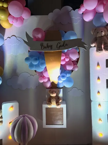 This whimsical baby shower featured large marquee letters, teddy bears nestled in pastel balloon clouds, and a custom hot air balloon prop, creating a dreamy and joyful atmosphere.