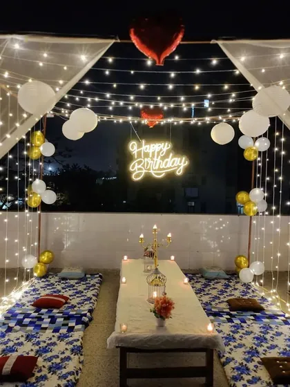 Here is a closer look at the dining setup under our fairy light canopy. The low table is decorated with candles and floral centerpieces, providing an intimate dining experience with a beautiful view of the Bengaluru night sky.