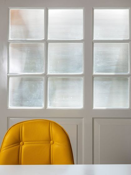 A close-up of the design details in the attic office, where modern yellow chairs contrast with the restored, fluted glass of the original doors.