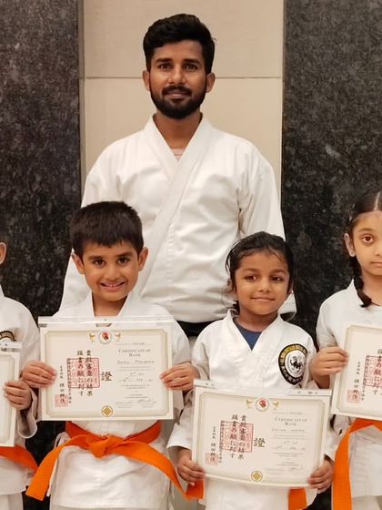 A group of young students beaming with pride as they show off their new orange belts. The early stages of karate are all about building a solid foundation in stances and basic techniques.