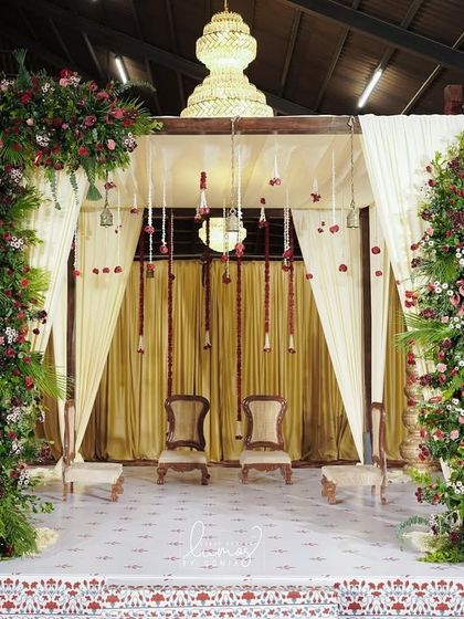 A traditional mandap setup with an arch of lush greenery and red florals. The design combines classic elegance with a touch of romance for a beautiful wedding ceremony.