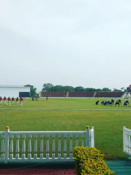 A wide view of the teams on the field during a competitive match. Our academy ensures players get the full experience of playing in large, well-maintained stadiums, preparing them for the pressures of professional cricket.