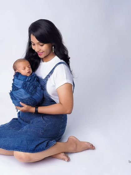 A simple and sweet portrait of a mother and her newborn. Dressed in matching denim, the mother cradles her baby, showcasing a quiet moment of connection.