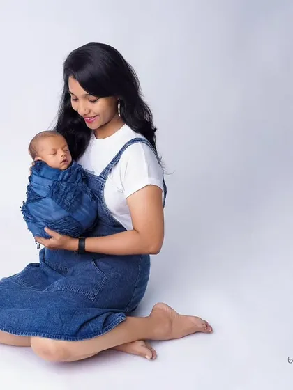 A beautiful portrait of a new mother holding her sleeping baby. The simplicity of the white background and matching outfits puts all the focus on the serene and loving connection between them.