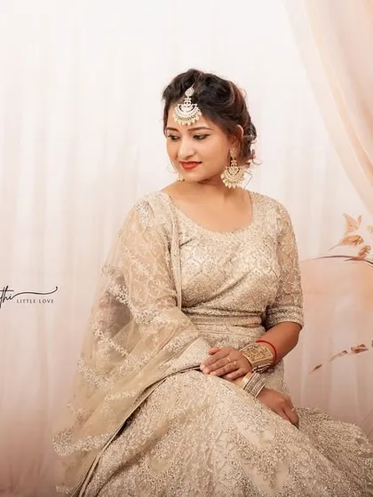 A beautifully composed seated portrait in a lehenga. The soft lighting and dreamy studio backdrop create a romantic and timeless feel.