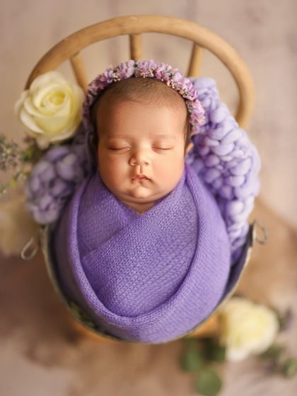 This is sweet Pakhi at two months old. The lavender wrap and floral crown complement her so beautifully, showing that we can capture stunning posed shots even with slightly older newborns.