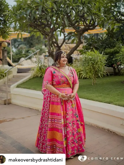 A stunning Mehendi look for this bride. The vibrant pink of her lehenga is complemented by a fresh and glowing makeup look, perfect for a festive outdoor celebration.