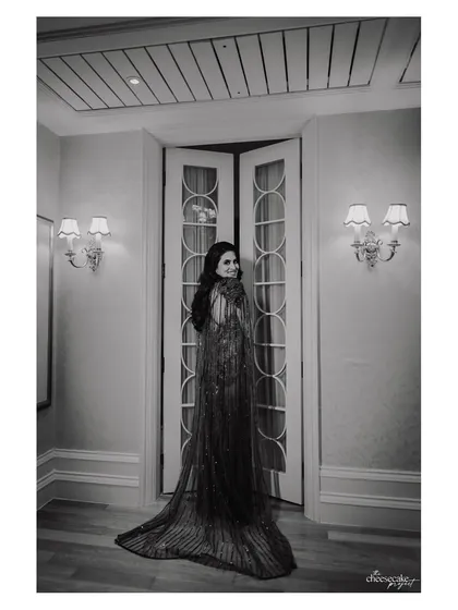 A full-length bridal portrait in black and white, emphasizing the silhouette and texture of her beautiful gown.