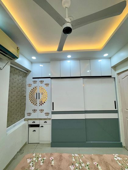 A bedroom design featuring a sliding wardrobe in green and white, with an attached pooja unit with beautiful jali work.