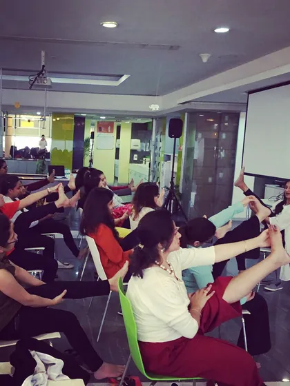 A seated leg stretch during a corporate yoga class. These simple exercises can be done right at your desk to improve circulation and prevent stiffness.