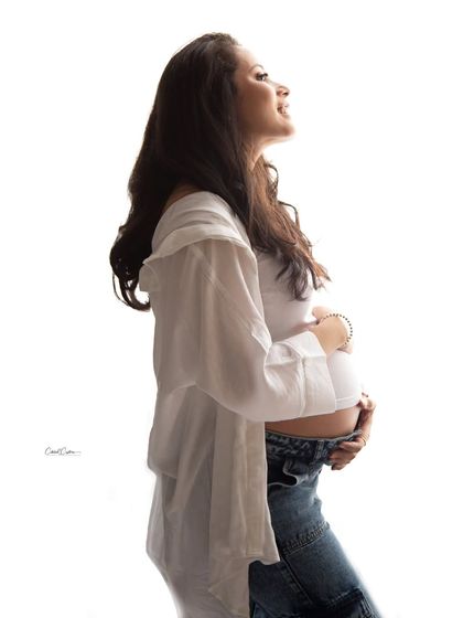 A bright, high-key portrait capturing the pure bliss of pregnancy. The mom-to-be is glowing in her simple and casual attire.