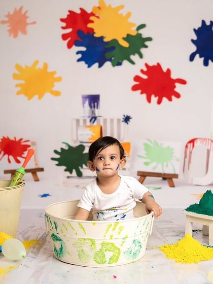 A shot from the Holi mini session, with the baby sitting in a tub surrounded by colorful powder and props.