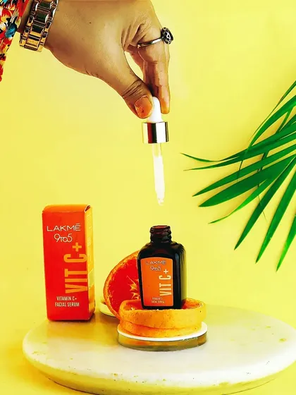 A wider shot of the Lakme Vitamin C serum setup, showing my hand with the dropper to add a human element and demonstrate its use.