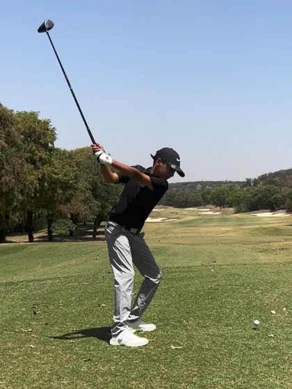 A junior player with his driver at the top of the swing, perfectly loaded and ready to unleash power.