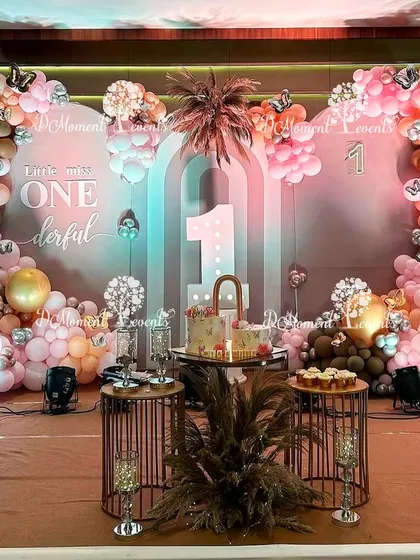 A close-up of the boho-themed stage, showing the "Little Miss ONEderful" sign, pampas grass, and the intricate balloon work in a palette of pink, brown, and gold.