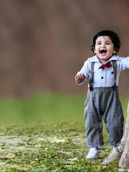 Capturing pure joy as a one year old boy laughs while playing peek a boo behind a large tree during his outdoor birthday photoshoot.