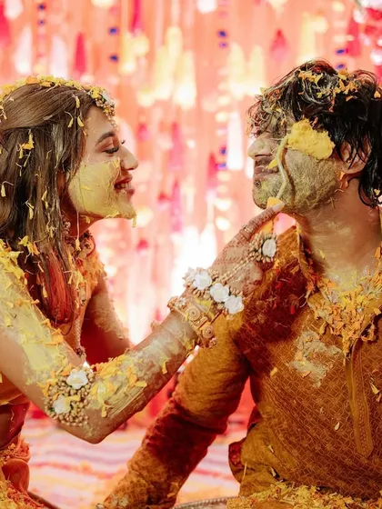 An intimate moment during the Haldi ceremony. The bride playfully applies turmeric to the groom, a sweet gesture of love and partnership amidst the joyful celebrations.