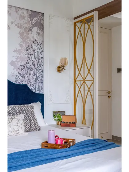 The interplay of textures and patterns is key to this design. The smooth velvet headboard, patterned cushions, and metallic partition create a rich, tactile experience.