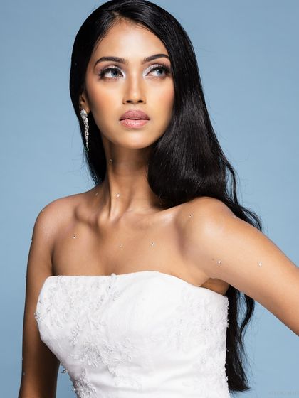 A beauty shot of a model in a white bridal gown, with a dreamy, upward gaze.