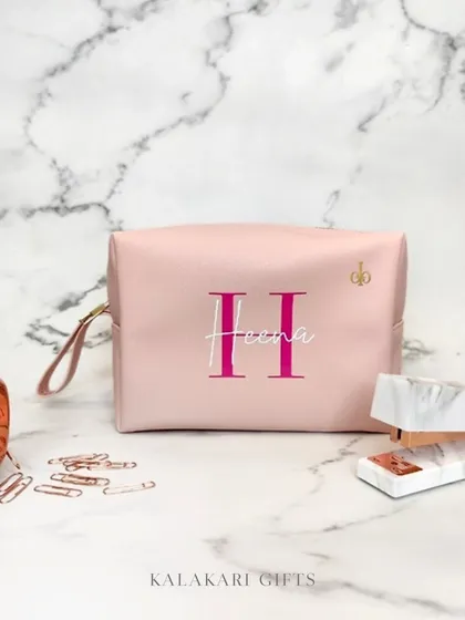 A personalized utility pouch in a soft pink, embroidered with the name "Heena." This versatile pouch is perfect for organizing makeup, stationery, or travel items.