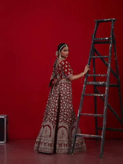 Another angle of the regal red bridal look, showing the intricate details of the outfit and the classic hair and makeup.