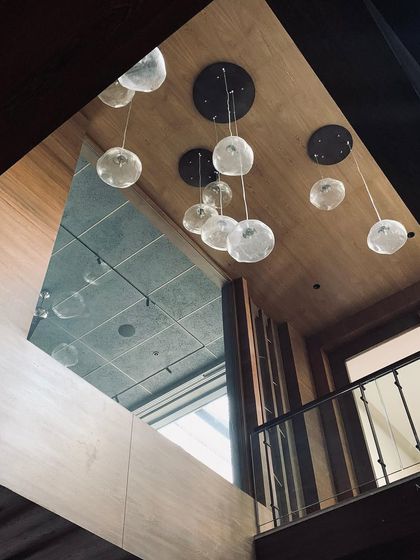 "Pebbles in the sky." A cluster of hand-blown glass pendant lights hangs in a double-height space, reflected in a mirror. This detail adds a touch of magic and lightness to the interior.