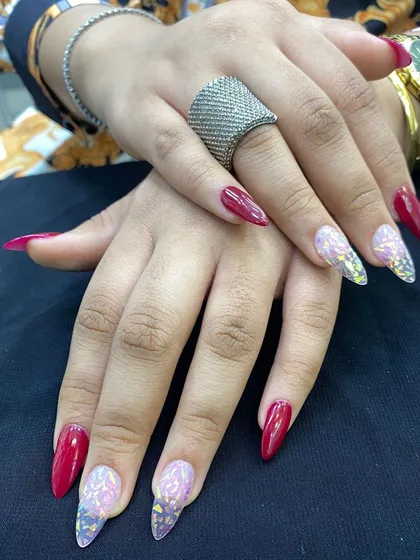 An example of student work featuring clear extensions with encapsulated butterflies and a bold red polish.