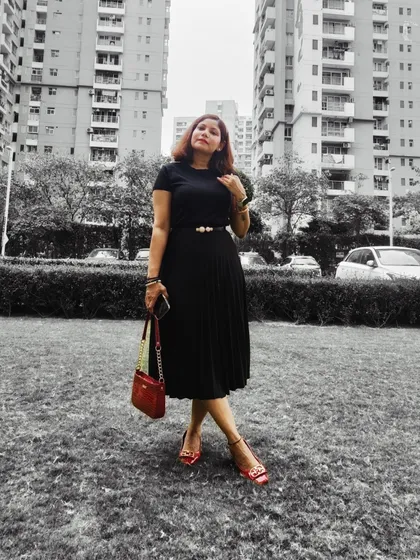 An all-black outfit is my personal favorite for its timeless elegance. Here, I’ve styled a pleated midi skirt and top with a statement belt and a pop of red from the bag and shoes, creating a sophisticated look perfect for any occasion.