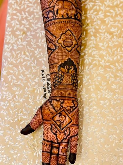 A beautiful design with a small portrait in a frame on the palm, surrounded by traditional peacock, elephant, and floral motifs.