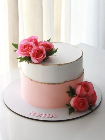 When elegance meets flavor. This two-toned pink and white cake with fresh roses has a delicious pineapple flavor inside.