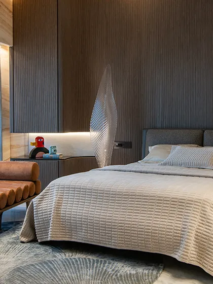 A thoughtful and refined bedroom design at World View Apartments. The palette is intentionally understated, allowing accents like the leather chaise lounge and brushed metals to add subtle glamour without overwhelming the serene vibe.