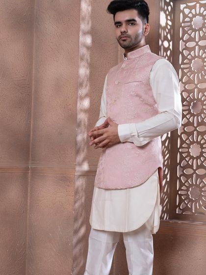 The rose pink bundi set, shown against a textured backdrop. The soft pastel tone is ideal for daytime celebrations and summer weddings, offering a sophisticated and stylish option.