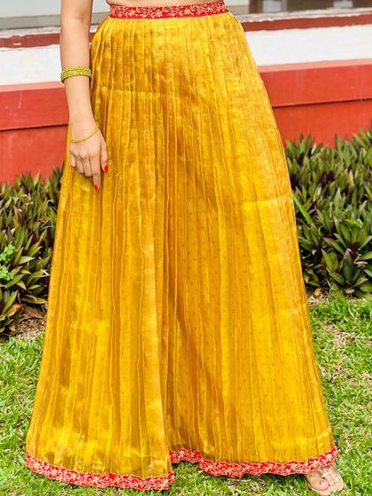 A close-up of the Kanchivaram tissue pleated skirt, showing the texture of the fabric and the contrasting red embroidered border.