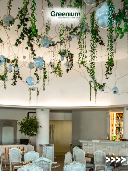A sophisticated restaurant or cafe rooftop design. The ceiling is adorned with hanging artificial vines and modern light fixtures, creating an enchanting atmosphere for guests.