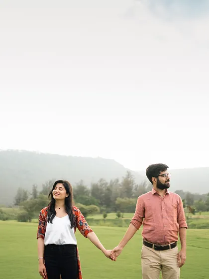 A wide shot of a couple holding hands in a beautiful green landscape. This photo emphasizes both their connection and the serene beauty of their surroundings.