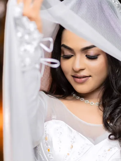 A model posing with a white veil, showing off the beautiful eye makeup for a Christian wedding look.
