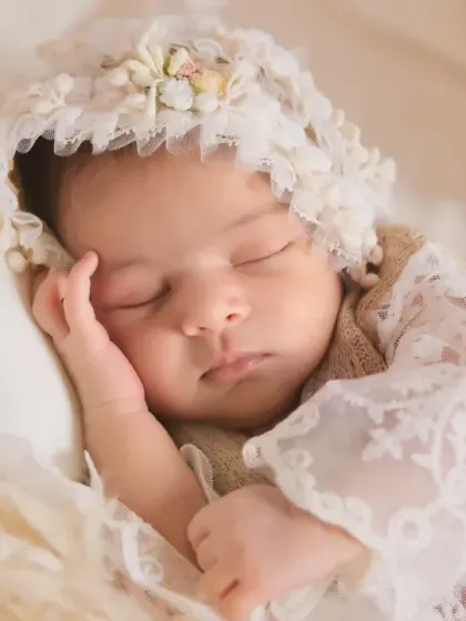 A close-up portrait focusing on the baby's face, framed by a delicate vintage lace bonnet. The soft lighting and dreamy focus create a truly fine art infant portrait.