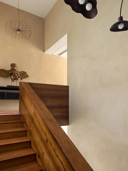 Another view of the stunning teak staircase, showing how it anchors the space. The warm wood tones are complemented by the earthy, textured finish of the walls and unique, artistic light fixtures.