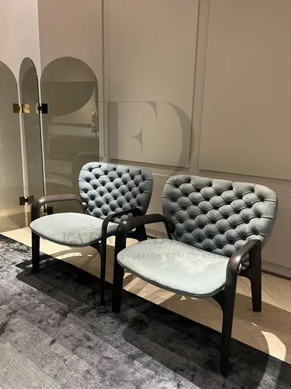 A pair of unique chairs with a tufted, light blue backrest and a solid wood frame. This design offers an interesting contrast between soft upholstery and a strong, architectural base.