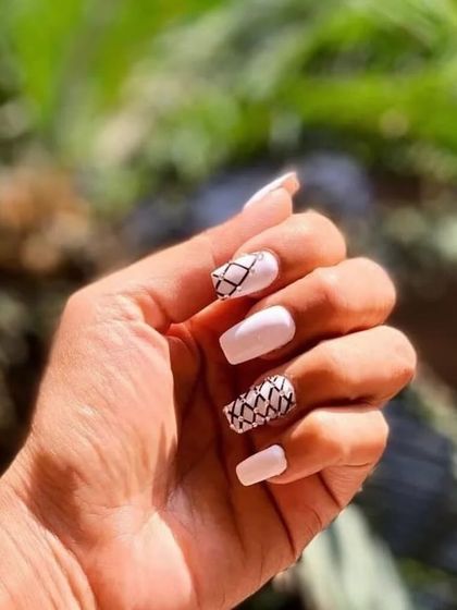 A chic and graphic black and white design, with a mix of solid white nails and nails featuring a hand-drawn crosshatch pattern.